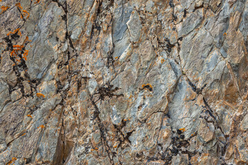Rugged natural rock face texture and background with triangular cracks