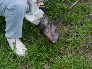 A woman cleans up dog excrement while on a walk.