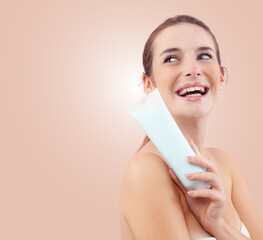 Portrait of a smiling young woman holding a cosmetic tube, which could be cream, sunscreen, shower...