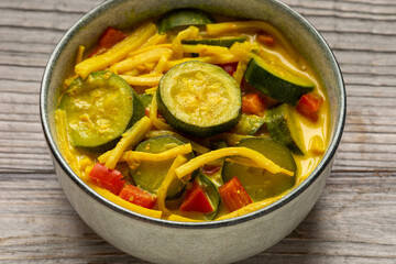 Vegan Thai yellow curry made of zucchini, red bell pepper, and bamboo shoots. Close-up.