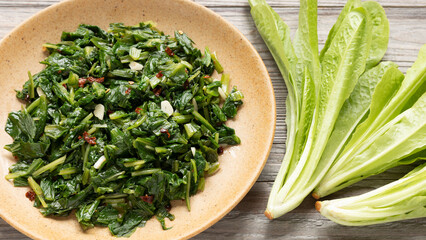 Roman-style chicory greens sautéed in olive oil with garlic and hot pepper flakes (Cicoria Ripassata alla Romana) - a traditional Italian side dish. Fresh, young chicory on the table.