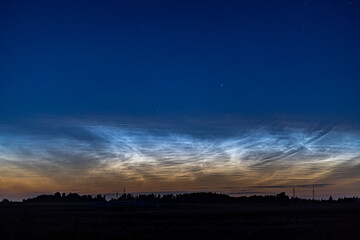 A stunning display of noctilucent clouds shimmering in the twilight sky above a serene natural landscape