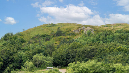 Lush Green Hill Under a Bright Blue Sky with Clouds