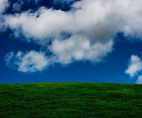 Fototapeta premium Green hill meets blue sky clouds