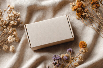 Cardboard box on linen fabric with dried flowers. Warm and cozy mockup for natural product branding