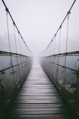 Fototapeta premium Misty Suspension Bridge Vanishing into Fog 