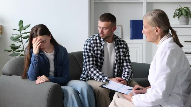 In vitro fertilization (IVF). Man comforting his upset wife during appointment with doctor in reproductive clinic