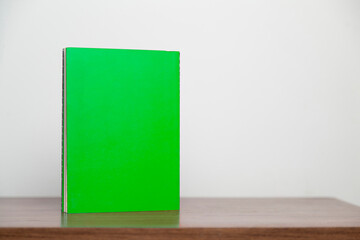 A green book on a wooden table. Book concept. Knowledge concept. 
Space for text.