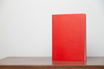 A red book on a wooden table. Book concept. Knowledge concept. 
Space for text.