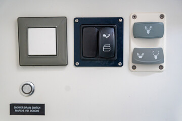 Close-up of control buttons for toilet flush and shower water system on a yacht. Practical detail,...