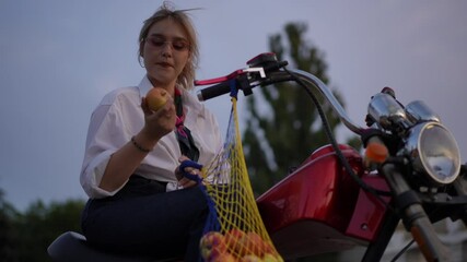 A stylish young woman riding a motorbike joyfully exploring the delightful experience of fresh fruits - Powered by Adobe