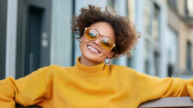 Cheerful outdoor fashion featuring bright smile, stylish sunglasses, and vibrant sweater ensemble