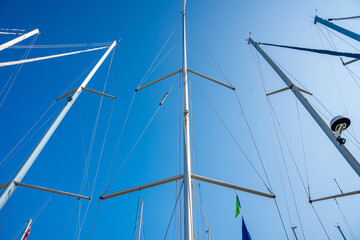 View from below of multiple sailboat masts rising into the sky in the marina on Hvar Island, Croatia. Vertical perspective, sailing lifestyle and maritime structure.