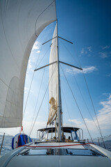 White sails filled with wind, seen from the bow of a sailing yacht near Croatia. Freedom, clean energy, adventure and mindful travel on the open sea.