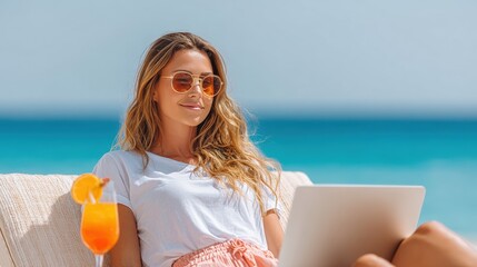 Woman in sunglasses working on a laptop while relaxing by the beach with a tropical drink in hand.