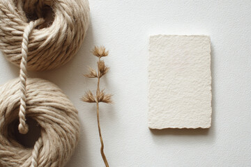 Fototapeta premium Natural fiber twine, dried grass, and textured paper card on white background create minimalist stationery flat lay with calm, organic, and neutral aesthetic
