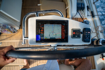 View from above of a man steering a sailing yacht using navigation display and control panel near Croatia. Precision, control and modern sailing lifestyle at sea.