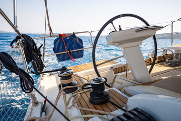 Cockpit of a sailing yacht with steering wheel, winches and ropes during navigation near Croatia. Sailing equipment, control and lifestyle at sea.