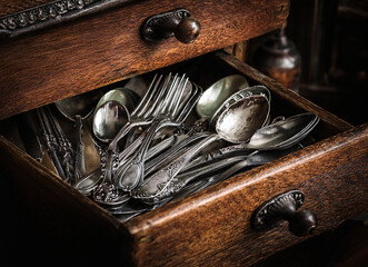 altes Silberbesteck mit Ornamenten in einem dunklen Holz Schublade