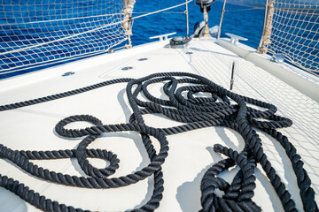 Black rope lying on the bow of a sailing yacht moving under full sails near Croatia. Marine detail, navigation, strength and motion at sea.