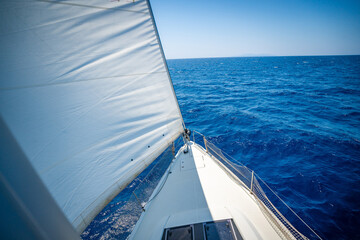 View from the mast down to the bow of a sailing yacht moving under full sails near Croatia. Freedom, adventure, yachting lifestyle and dynamic sea travel.