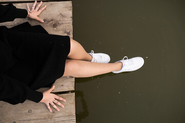 Girl in a dress sits on boards by the water