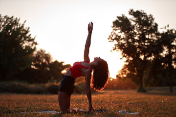 Woman practicing yoga and stretching in the park on a hot sunny summertime day.