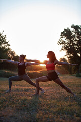 Two women practicing yoga and stretching in the park on a hot sunny summertime day.