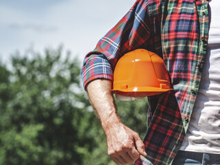 Handsome man and work helmet. Closeup, outdoors. Congratulations for family, loved ones, friends and colleagues. Concept of preparation for the national holiday