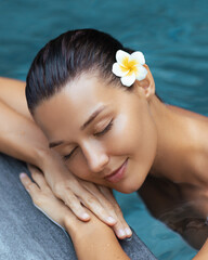Peaceful Woman with Flower Relaxing by Pool in Luxury Spa Setting