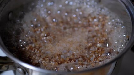 A closeup view of grains boiling in a pot, vividly showcasing the intricate cooking process and bubbles forming