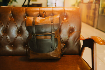 Stylish leather backpack placed on a vintage upholstered chair in a cozy indoor setting with a warm...