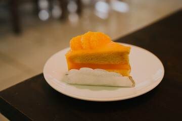 Delicious orange layered cake slice served on a white plate in a warm and inviting café setting