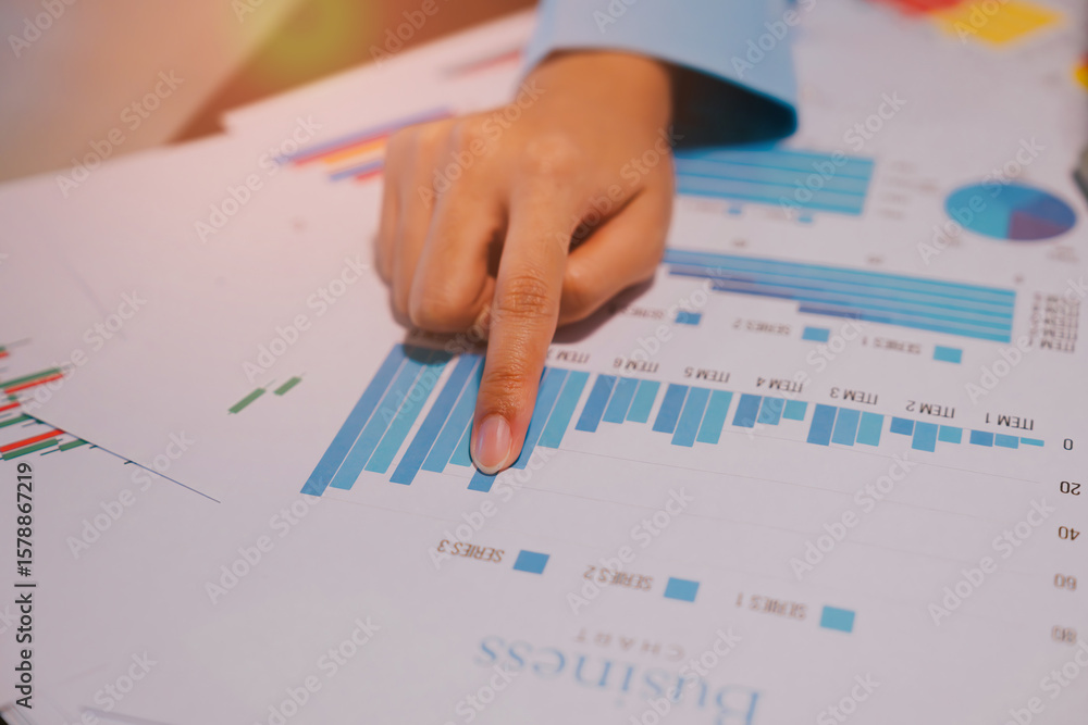 Poster close-up of business analyst pointing at graphs and charts with data insights in office environment
