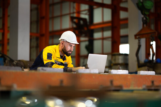 Laptop computer : blue collar working production line : Caucasian man engineer worker working control sheet metal roof tile roll forming machine at metal sheet profiling factory. Industrial production