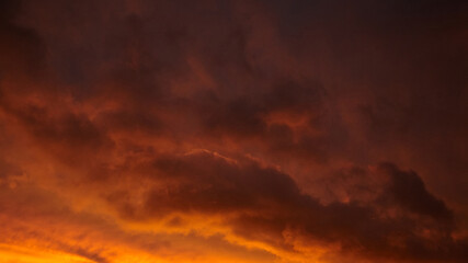 Dramatic sunset sky with vibrant orange and purple hues, showcasing textured clouds illuminated by the fading light, creating a stunning natural atmosphere and visual spectacle