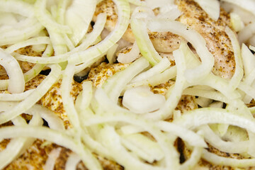 Sliced onions layered over seasoned chicken, creating a flavorful dish, showcasing the preparation...