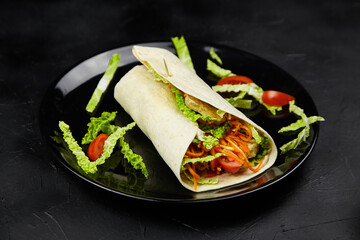 Freshly prepared wrap filled with colorful vegetables, including lettuce, carrots, and tomatoes, served on a sleek black plate, showcasing vibrant culinary presentation and healthy eating