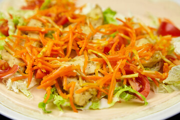 Fresh salad with shredded carrots, lettuce, and tomatoes arranged beautifully on a plate, showcasing vibrant colors and healthy ingredients in a delightful presentation