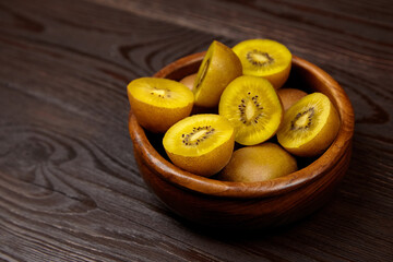 Fresh golden kiwis arranged in a wooden bowl on a rustic wooden table, showcasing their vibrant color and unique texture, perfect for healthy eating and culinary inspiration
