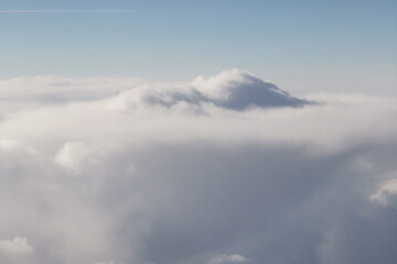 Soft white clouds blanket the sky, creating a serene atmosphere above the horizon, with hints of...