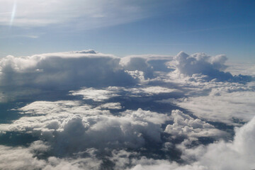 Aerial view of fluffy white clouds illuminated by sunlight, creating a serene atmosphere above the...