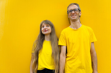 Man and Woman in Yellow Outfits Smiling Against a Matching Yellow Background
