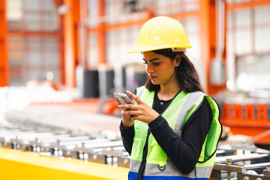 Cell phone smartphone : blue collar working production line : Indian female engineer worker working sheet metal roof tile roll forming machine at metal sheet profiling factory. Industrial production