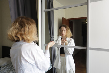 Woman Looks in Mirror in Shock as Hair Falls Out, Facing Chemotherapy Side Effects at Home