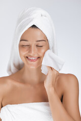 Happy Woman Wiping Face With Towel in Soft Light Skincare Concept
