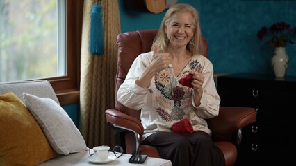Portrait of mature woman sits in a brown leather recliner, smiling looking at camera and giving a...