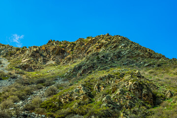 Serene mountain landscape with rocks and vegetation, daytime, Kyrgyzstan