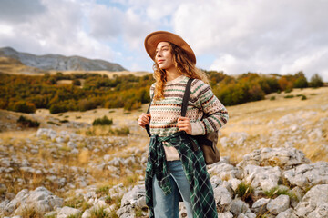Young woman hiker with a briefcase on a mountain trail enjoying nature. Traveler on a hike and...