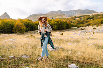 Young woman hiker with a briefcase on a mountain trail enjoying nature. Traveler on a hike and...